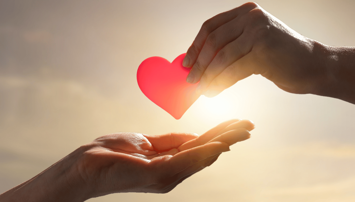 Hand places heart on another hand as symbol of charity